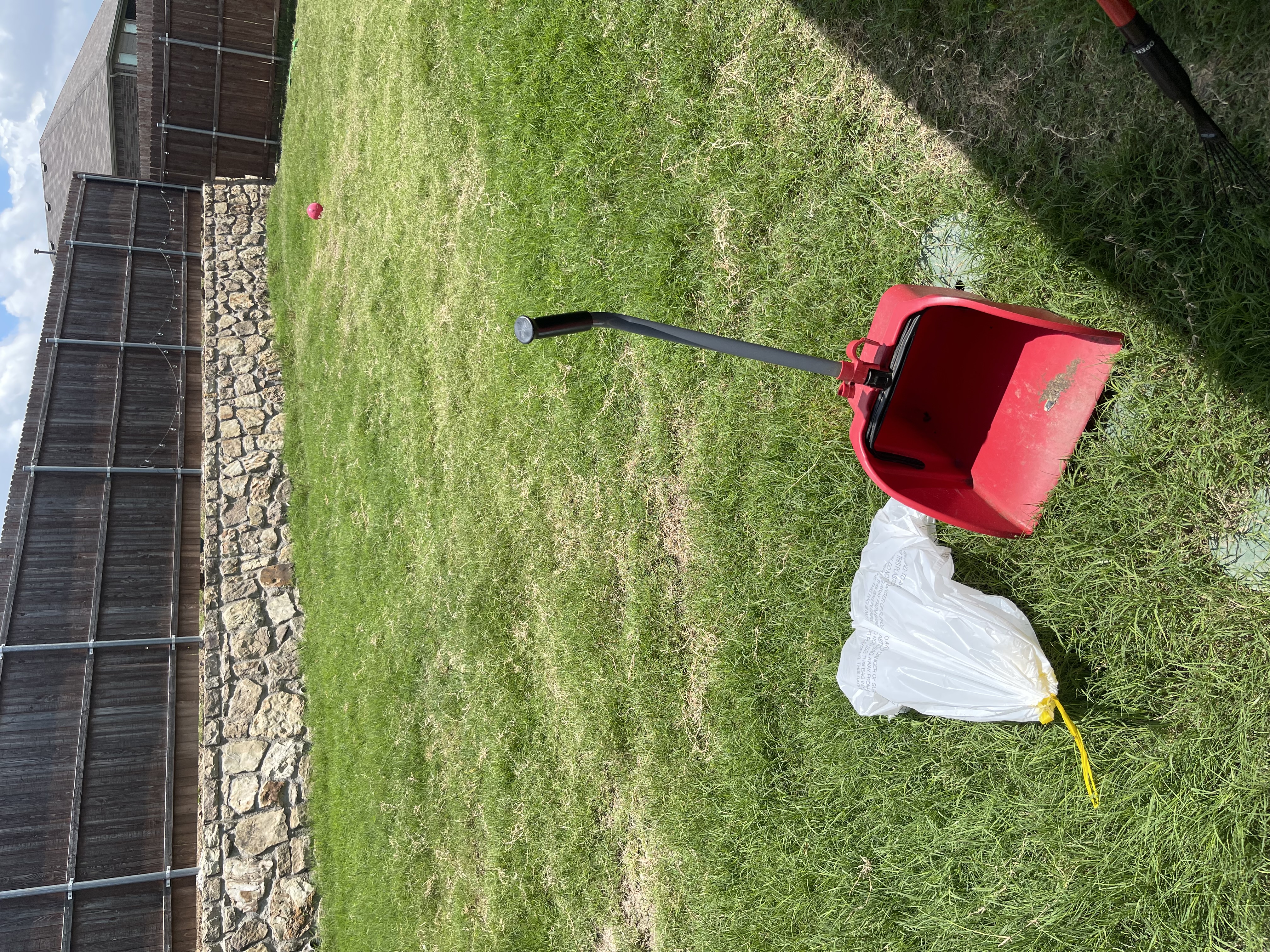 A1 Scoop Warriors dog poop removal service completed on a green yard bordered by a stone retaining wall